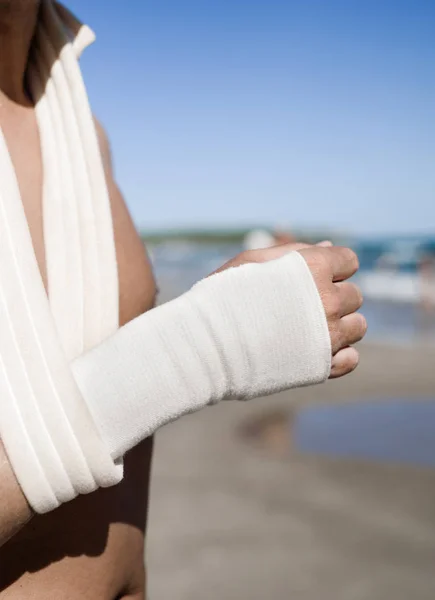 Adam bileğini bir bandaj ile sahilde — Stok fotoğraf