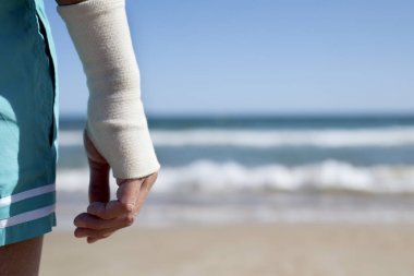man on the beach with a bandage in his wrist clipart