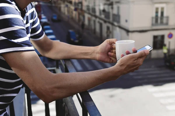 Jeune homme utilisant son smartphone dans le balcon — Photo