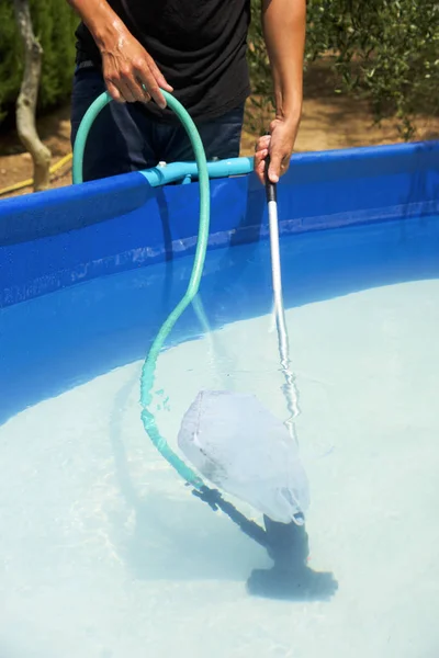 Young man cleaning a portable swimming pool — Stock Photo, Image