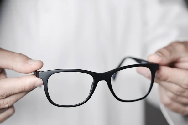 Optician man bringing a pair of eyeglasses — Stock Photo, Image