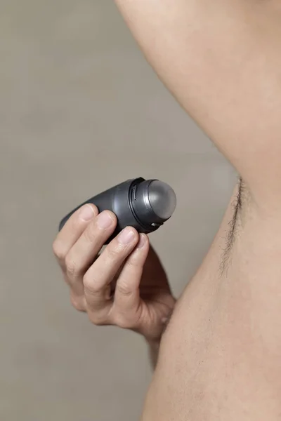 Young man applying deodorant to his armpits — Stock Photo, Image