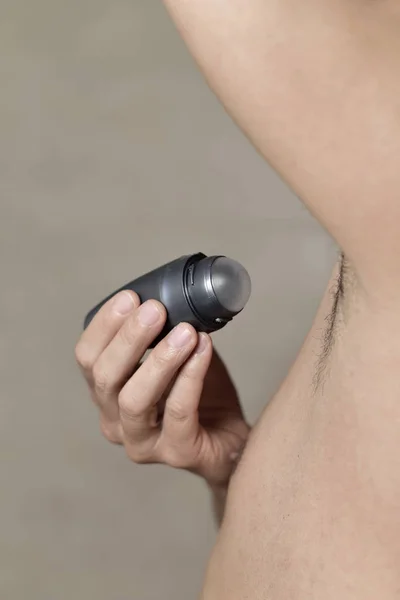 Genç adam onun koltukaltı deodorantı uygulama — Stok fotoğraf