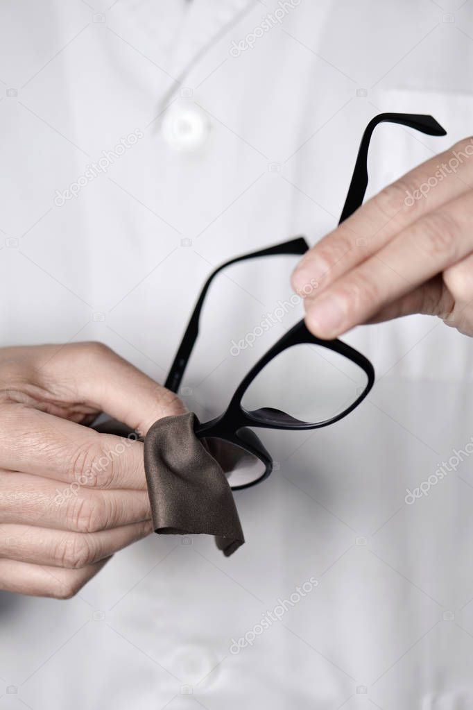 optician man cleaning a pair of eyeglasses