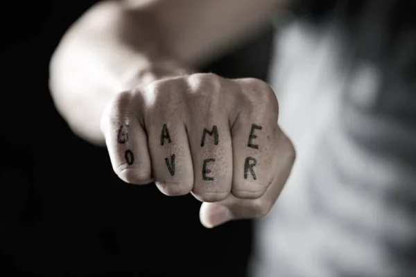 Text game over in the knuckles of a young man — Stock Photo, Image
