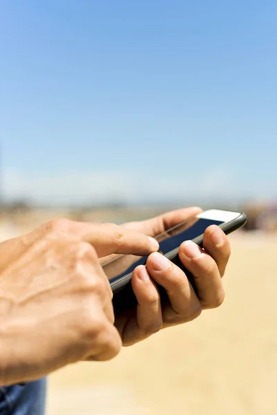 Man met behulp van een smartphone naast het strand — Stockfoto