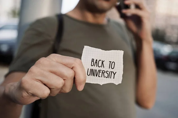 Hombre con una nota con el texto de vuelta a la universidad — Foto de Stock