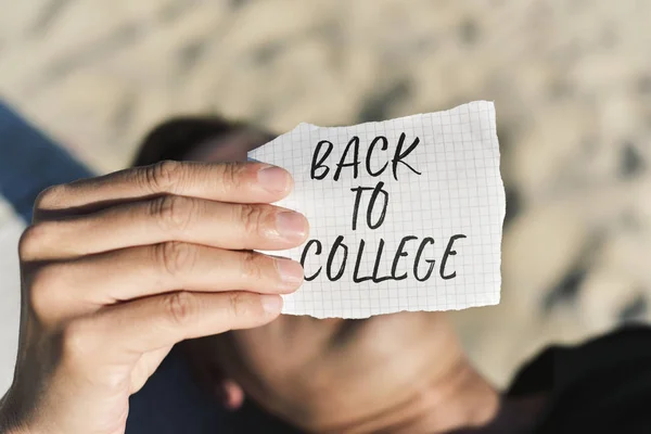 Estudiante con una nota con el texto de vuelta a la universidad — Foto de Stock