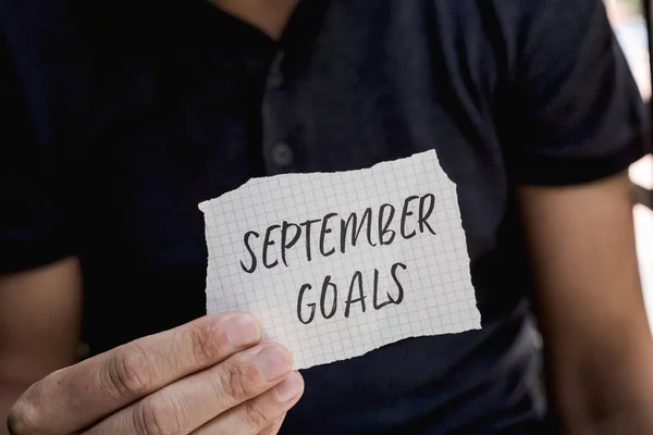 Man with a note with the text sSeptember goals — стоковое фото