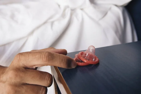 Joven en la cama a punto de tomar un condón — Foto de Stock