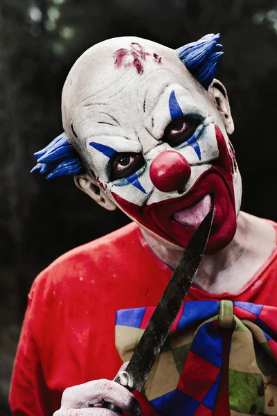 Gruseliger böser Clown mit Messer im Wald — Stockfoto