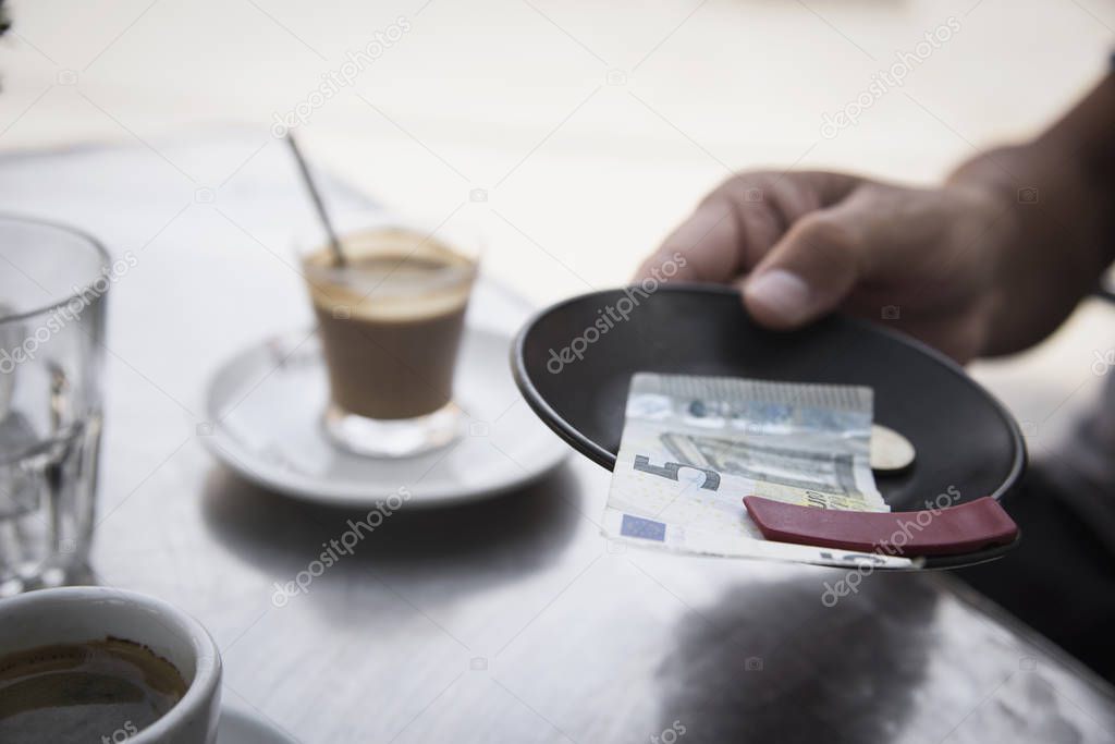 young man paying the bill in the terrace of a cafe