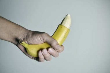 man with a banana with the tip of its skin removed clipart
