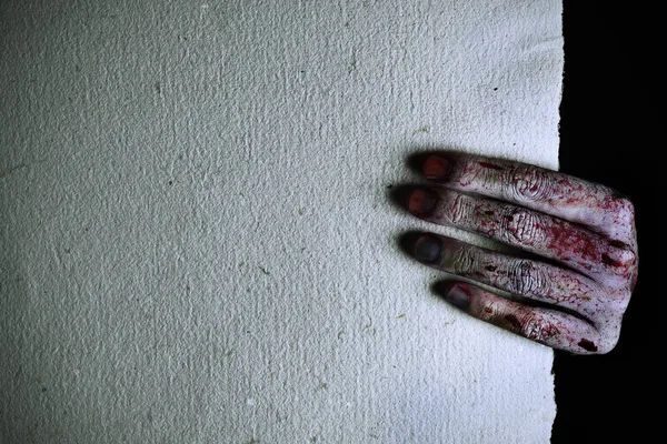 Skrämmande och blodiga hand som håller ett tomt papper — Stockfoto