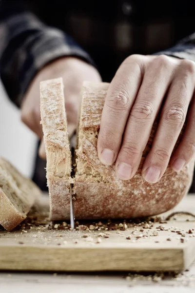 スペルト小麦のパンを切る男ロールします。 — ストック写真