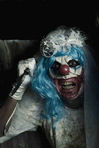 Skrämmande onda clown i en brud klä svingar en kniv — Stockfoto