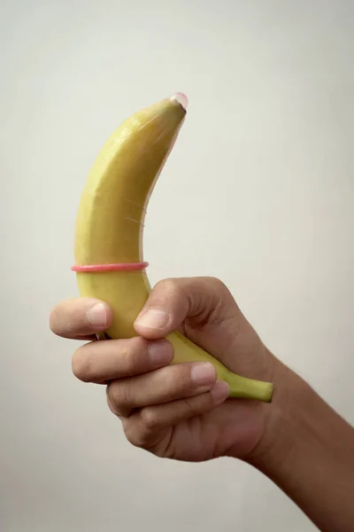 Uomo che tiene una banana con un preservativo — Foto Stock