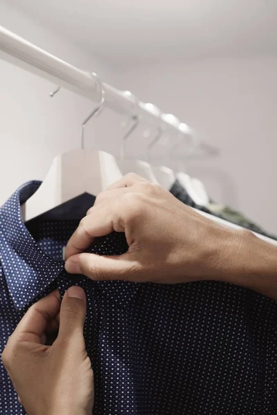 Jovem pendurado ou despendurado uma camisa — Fotografia de Stock