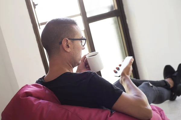 Man een kop koffie en met behulp van zijn smartphone — Stockfoto