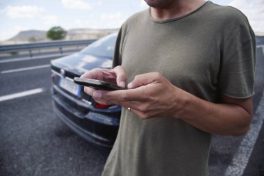 yolda bir araba yanındaki bir akıllı telefon kullanan adam