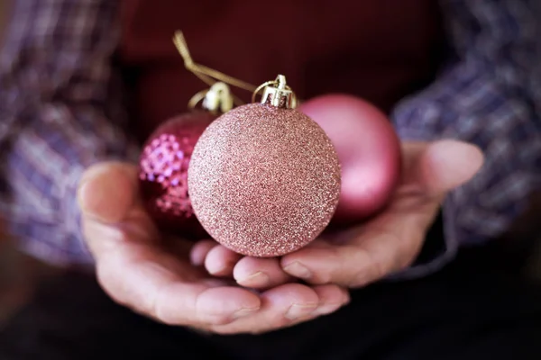 Yaşlı adam ellerini Noel topları ile — Stok fotoğraf