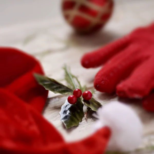 Santa hat, christmas ball, red gloves and holly — Stock Photo, Image