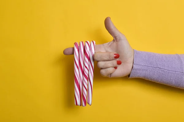 Bastones de caramelo en el dedo índice de una joven — Foto de Stock