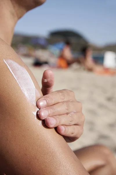 Hombre aplicando protector solar a sus brazos — Foto de Stock