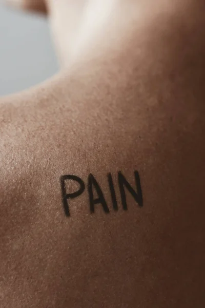 Man met het woord pijn in zijn rug — Stockfoto