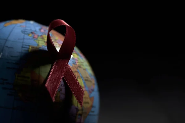 Globus mit roter Schleife für den Kampf gegen Aids — Stockfoto
