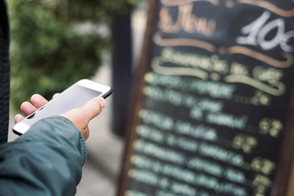 Homem usando um smartphone na frente de um restaurante — Fotografia de Stock