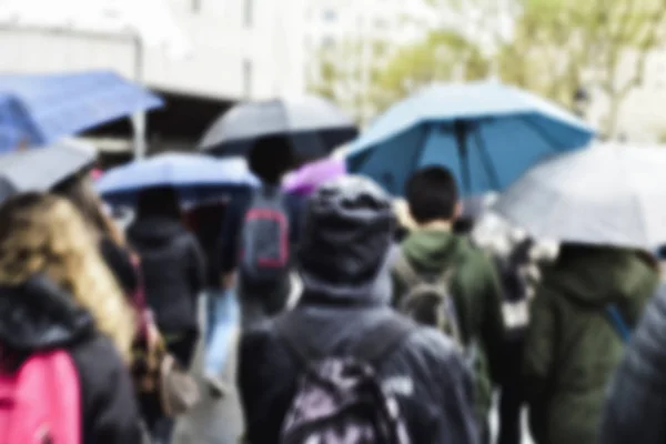 Θολή ανθρώπους που περπατούν κάτω από τη βροχή σε μια πόλη — Φωτογραφία Αρχείου