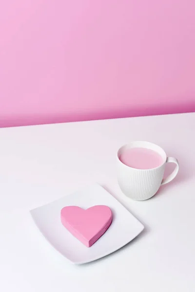 Coeur rose dans une assiette et une tasse de milkshake rose — Photo