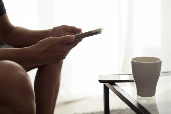 Jovem sentado em um sofá usando um tablet — Fotografia de Stock