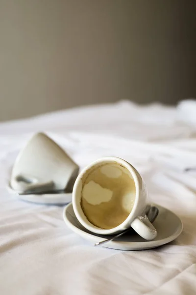 Xícaras vazias de café em uma cama não feita — Fotografia de Stock