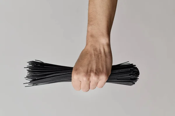 Mann mit einem Bund ungekochter schwarzer Spaghetti — Stockfoto