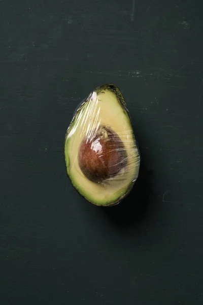 Halve avocado gewikkeld in plasticfolie — Stockfoto