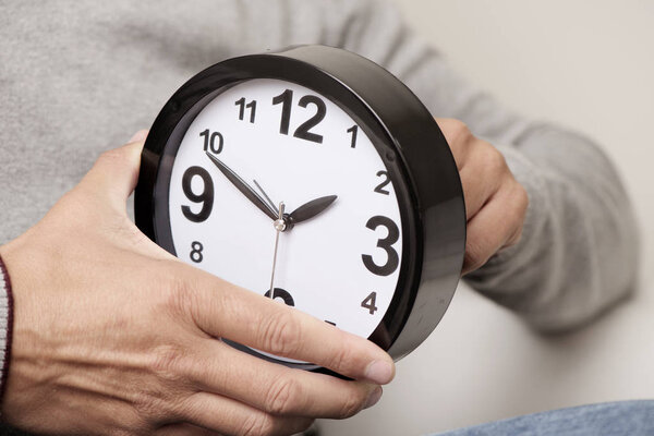 man adjusting the time of a clock