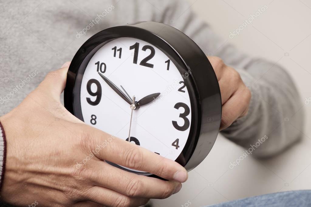 man adjusting the time of a clock