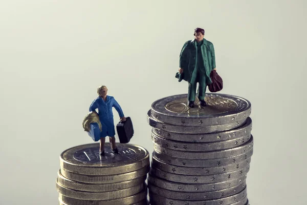 Мініатюрна жінка і чоловік на купах монет євро — стокове фото