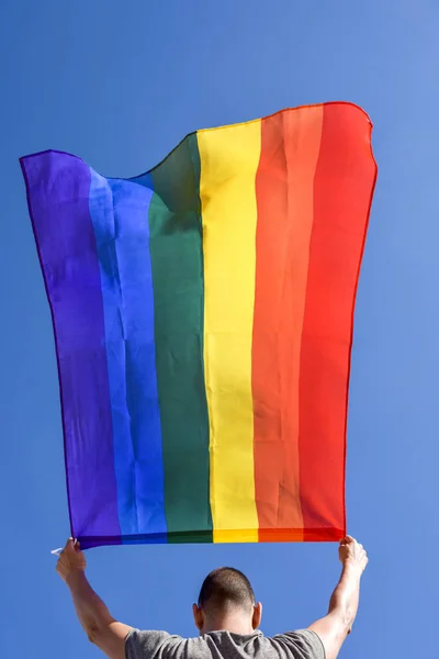 Joven con una bandera de arco iris — Foto de Stock