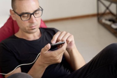 fasulye çanta sandalyede oturan onun smartphone kullanan adam