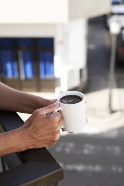 Νεαρός άνδρας έχοντας ένα καφέ στο μπαλκόνι — Φωτογραφία Αρχείου