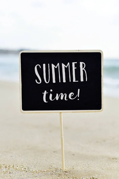 Zomertijd van tekst in een bord op het strand — Stockfoto