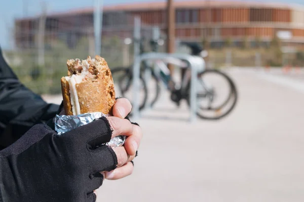 Jovem ciclista homem comendo um sanduíche — Fotografia de Stock