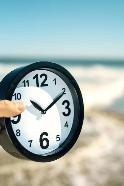 Ung man med en klocka på stranden — Stockfoto