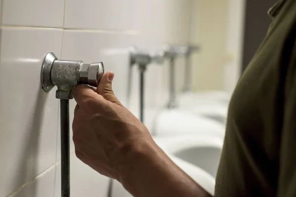 Joven usando un urinario en un baño público —  Fotos de Stock