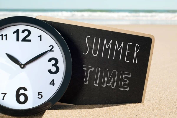 Klocka på sommaren beach och text — Stockfoto