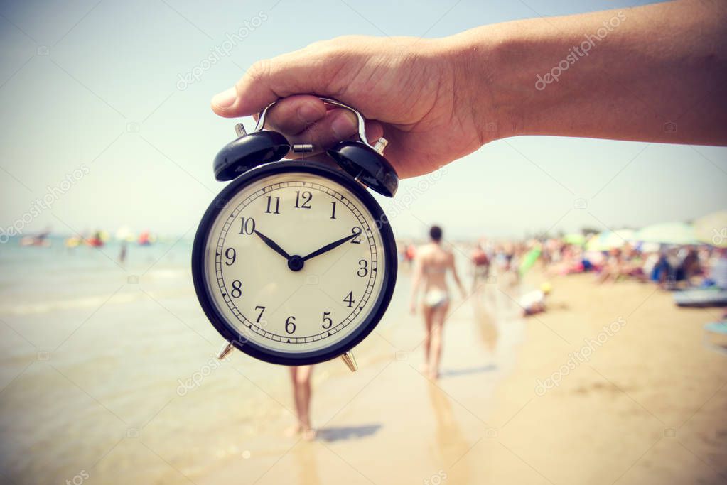 young man with an alarm clock on the beach