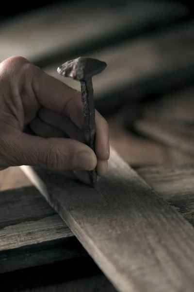 Man driving a nail on a wooden cross — Stock Photo, Image